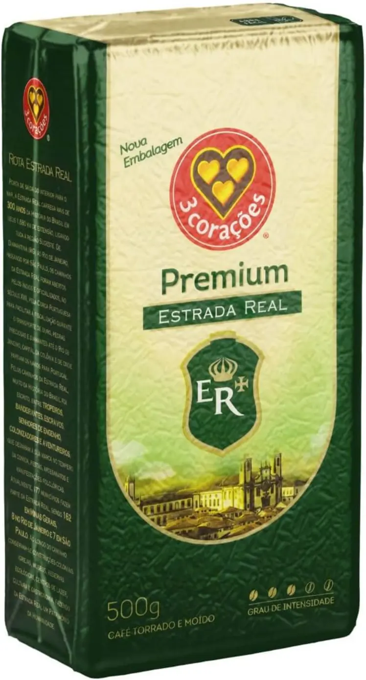 Xícara de café fumegante com a embalagem do 3 Corações Café Torrado e Moído Premium Estrada Real ao fundo.