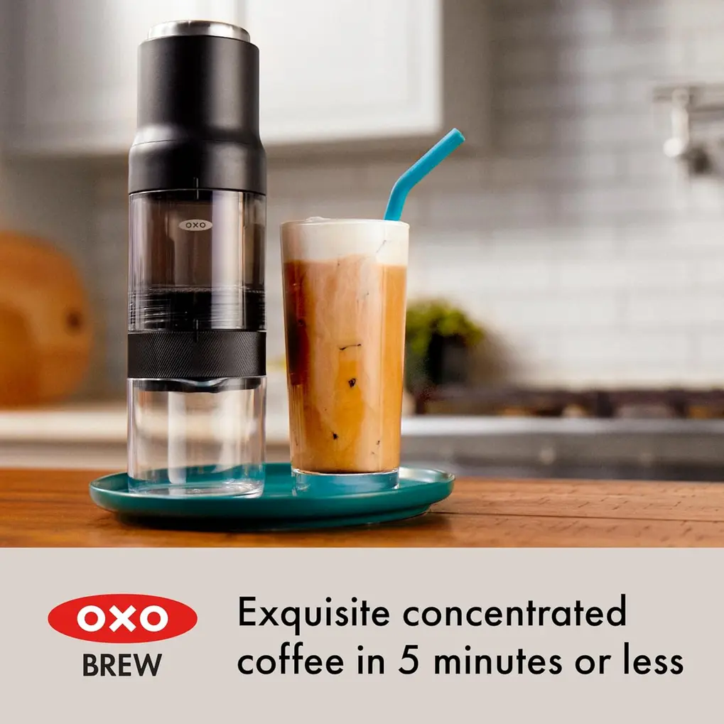 Cafeteira OXO Brew Rapid Brewer preta montada ao lado de uma xícara de café pronto.