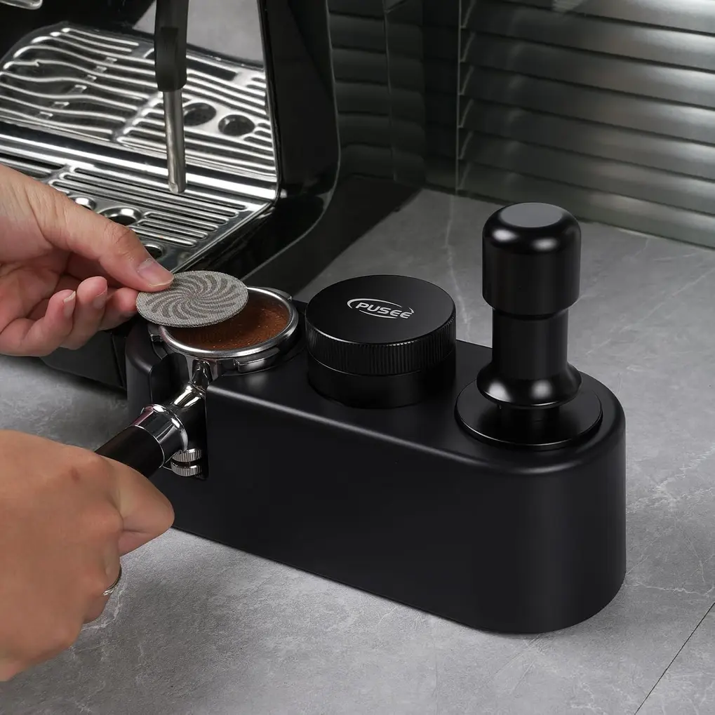 Estação de adulteração de café expresso PUSEE preta em uso, com portafilter, tamper e distribuidor.