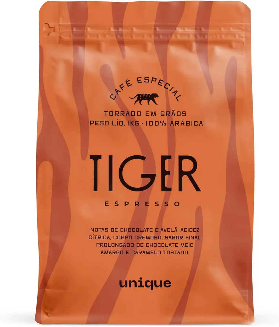 Grãos de café Unique Tiger Espresso sendo medidos com uma colher, com a embalagem ao fundo