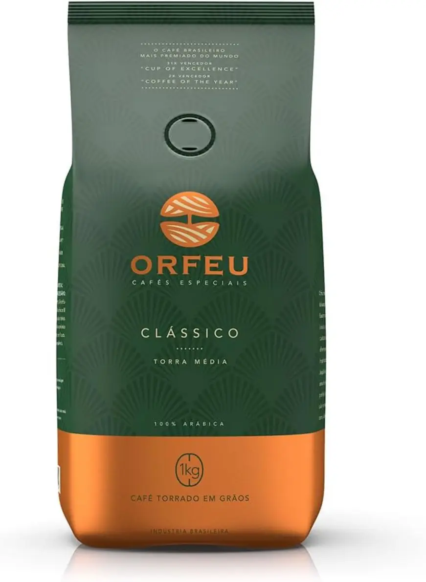 Mão segurando grãos de café Orfeu Clássico, com a embalagem do produto desfocada ao fundo.